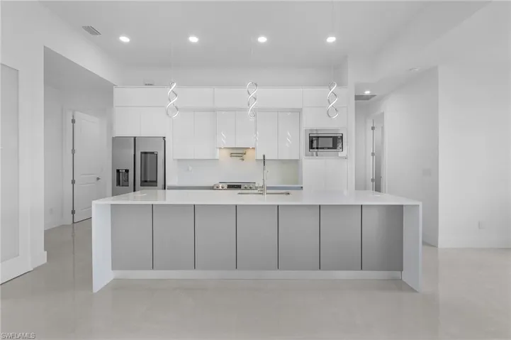 Kitchen with white cabinets, a kitchen island with sink, stainless steel appliances, and sink