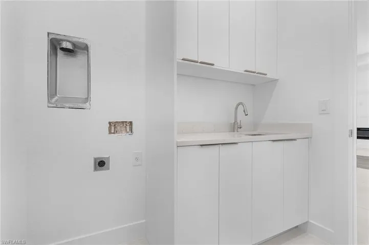 Washroom with cabinets, electric dryer hookup, and sink