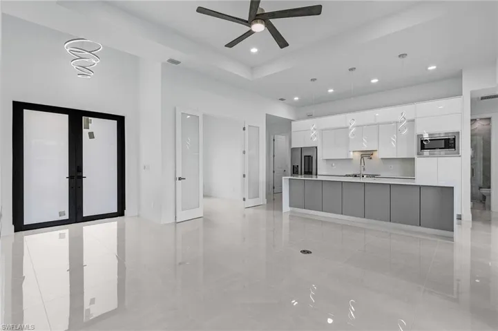 Kitchen with appliances with stainless steel finishes, hanging light fixtures, white cabinets, ceiling fan, and a spacious island