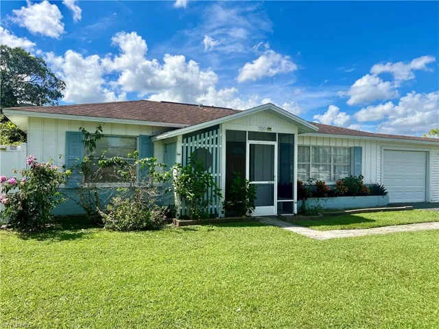 View of front of house featuring a sunroom, a front lawn, and a garage