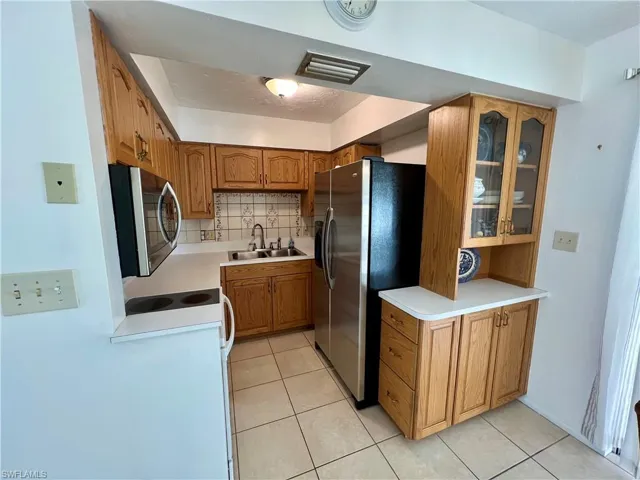 Kitchen featuring light tile patterned flooring, appliances with stainless steel finishes, backsplash, and sink