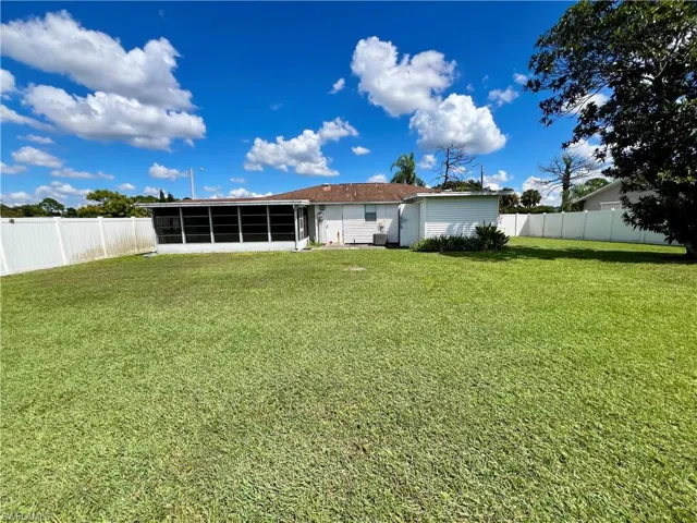 Back of property with a lawn and a sunroom
