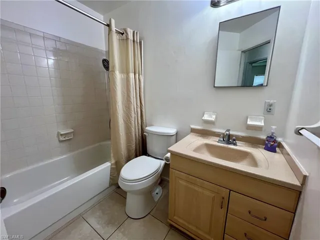 Full bathroom featuring shower / tub combo with curtain, vanity, toilet, and tile patterned floors