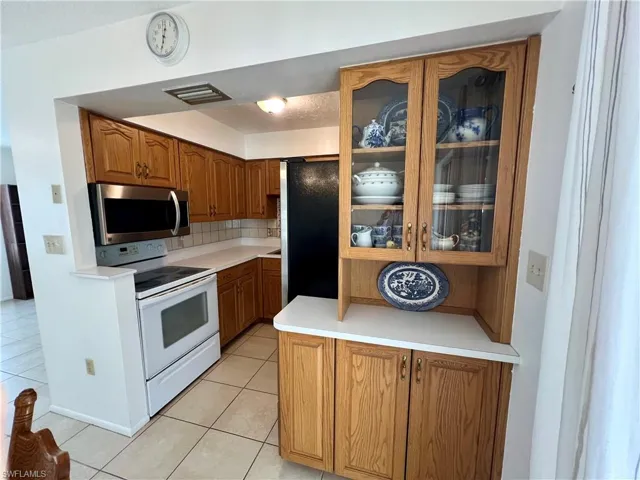 Kitchen featuring light tile patterned flooring, appliances with stainless steel finishes, and backsplash