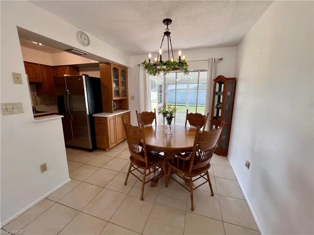 Dining space with a textured ceiling, light tile patterned flooring, and an inviting chandelier