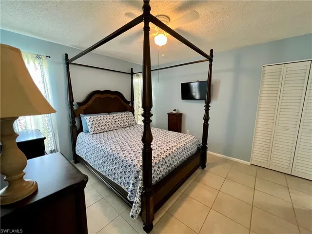 Primary Bedroom with ceiling fan, a textured ceiling, and light tile patterned floors