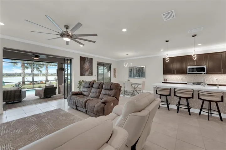 Living area with ornamental molding, light tile patterned flooring, recessed lighting, a ceiling fan, and a water view