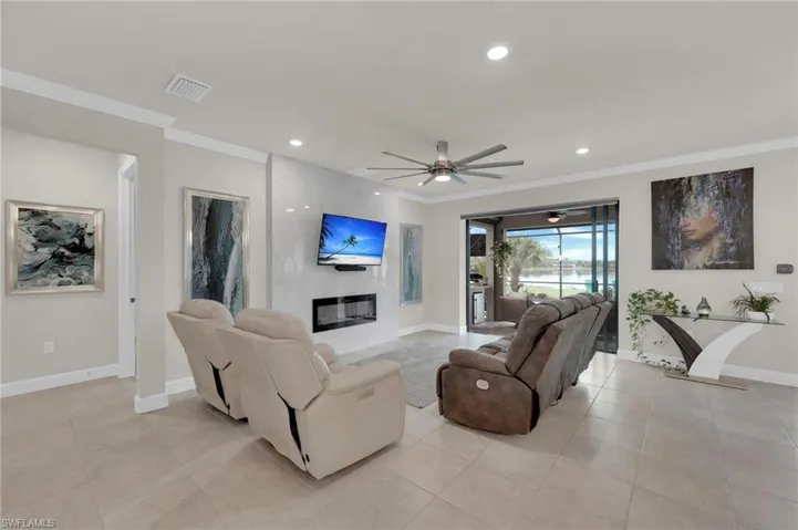 Living area with ornamental molding, light tile patterned flooring, recessed lighting, a ceiling fan, and a water view