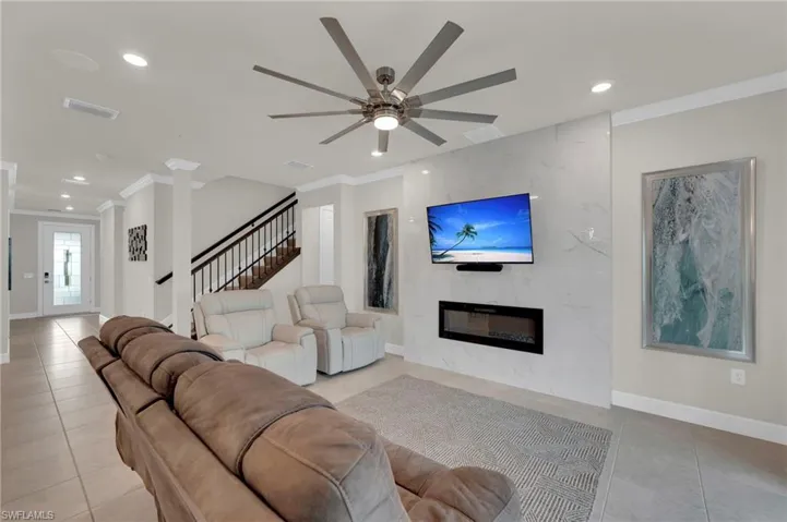 Living area featuring ornamental molding, recessed lighting, stairs, a premium fireplace, and a ceiling fan