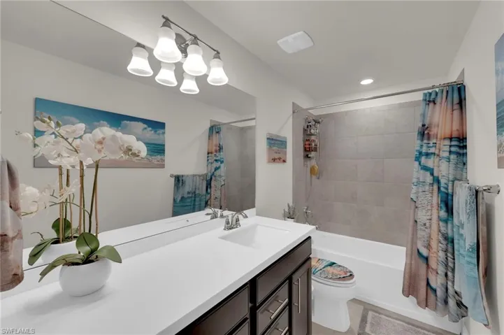 Bathroom featuring shower / bath combo with shower curtain, vanity, and recessed lighting