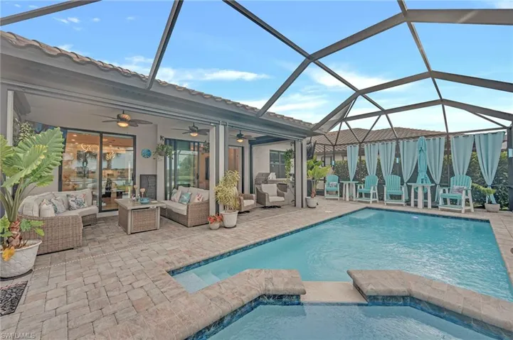 View of pool featuring a sunroom, ceiling fan, a patio, glass enclosure, and a pool with connected hot tub