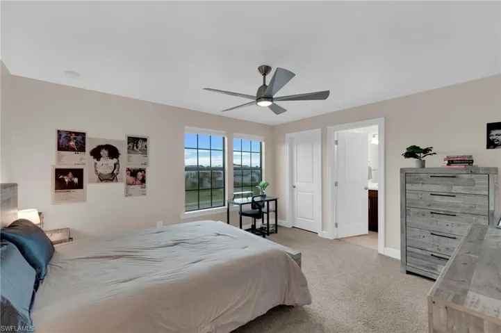Bedroom with light carpet, ceiling fan, and ensuite bathroom