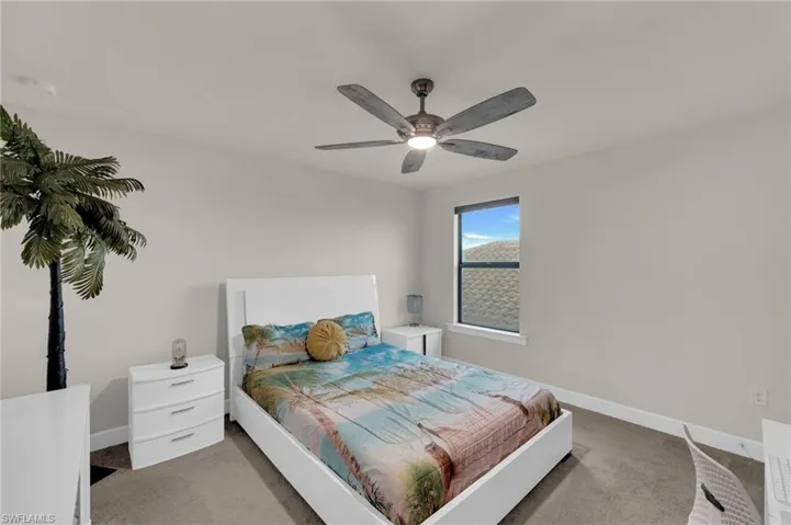 Carpeted bedroom featuring baseboards and a ceiling fan