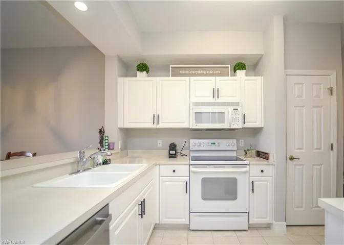 Kitchen with white appliances, white cabinets, and light countertops