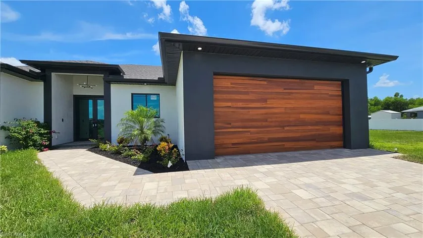 View of front of house with stucco siding, a garage, and decorative driveway