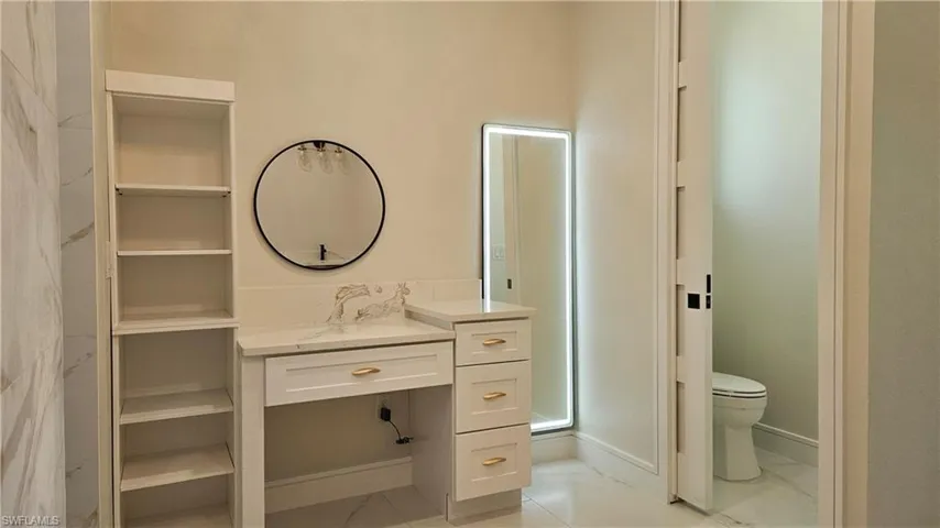 Bathroom featuring light marble-like finish floors, vanity, and a closet