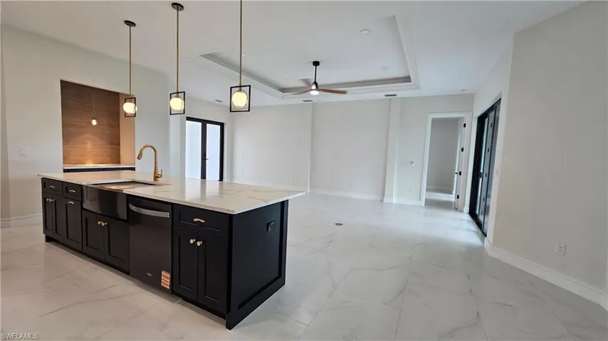 Kitchen featuring decorative light fixtures, a tray ceiling, and a coffee bar