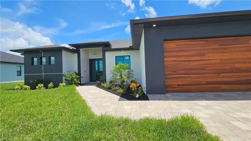 View of front facade featuring stucco siding, a front lawn, and a garage