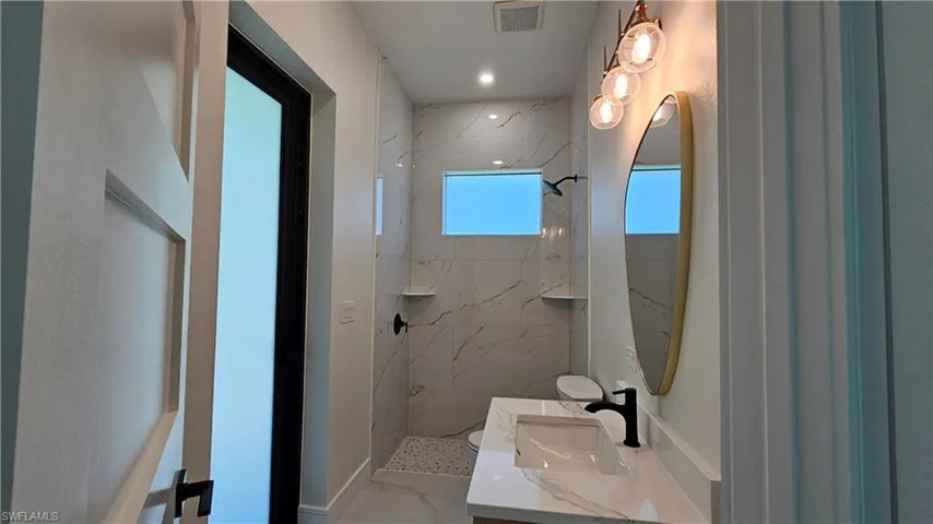 Guest bathroom with vanity, a marble-like finish shower and floors