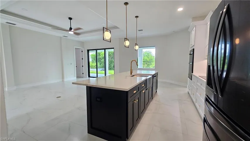 Kitchen with black and  white cabinets, french doors refrigerator, and a kitchen island with farm style sink