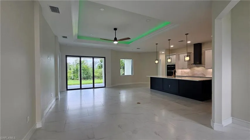 Living room featuring a tray ceiling, a ceiling fan, light marble finish floors, and recessed lighting