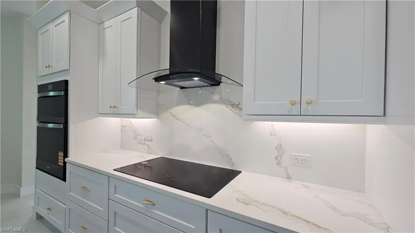 Kitchen with black glass electric cooktop, and black stainless steeel and tempered glass exhaust hood