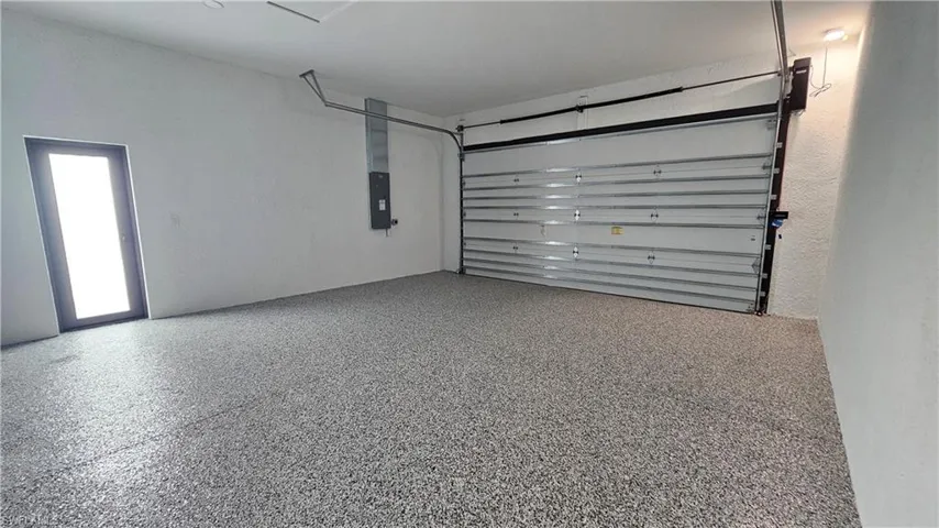 Two car garage space featuring epoxy finish and glass door to the exterior of the house