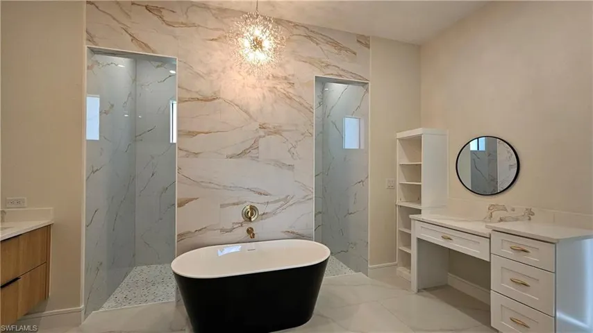 Bathroom with vanity, light marble-like finish floors, a freestanding tub, and a chandelier