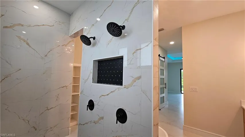 Detailed view of the shower with double shower heads and recessed shampoo shelf