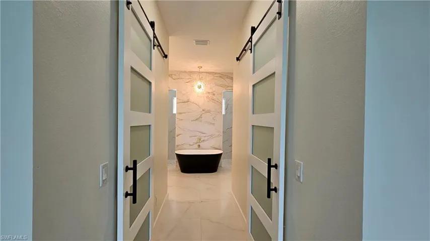 Bathroom entryway featuring two barn doors for Hers and His closet