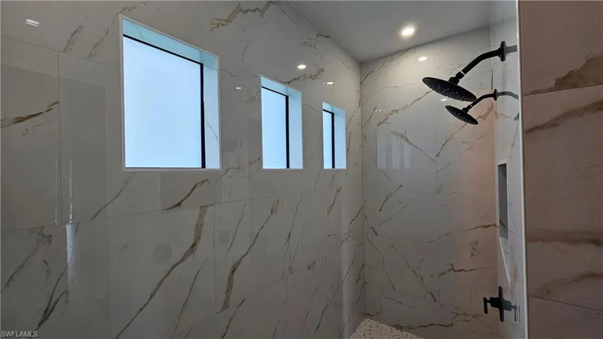 Bathroom with a marble-like finish shower and recessed lighting