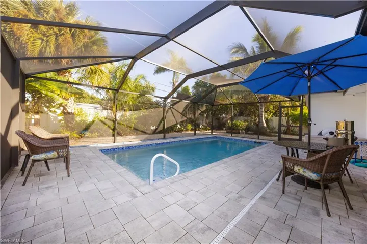 Outdoor pool featuring a sunroom, a patio area, and glass enclosure