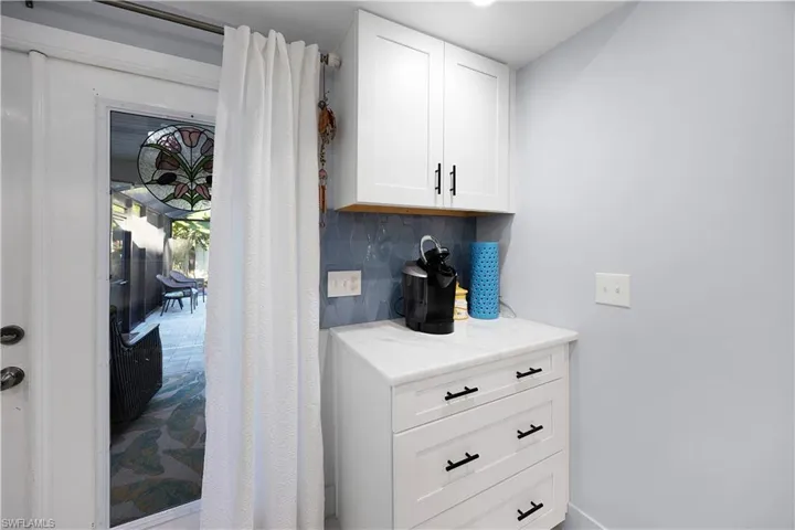 Bar area with white cabinetry, tasteful backsplash, and light stone counters