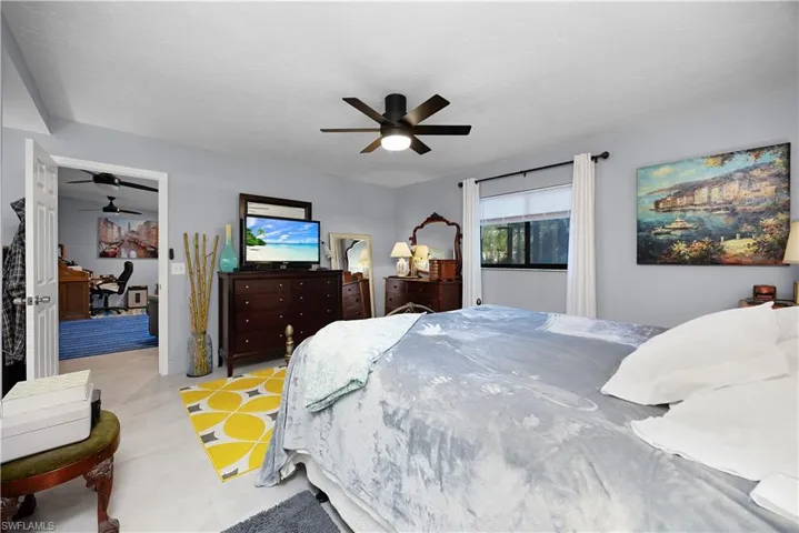 Tiled bedroom with an office area, a ceiling fan, and a textured ceiling
