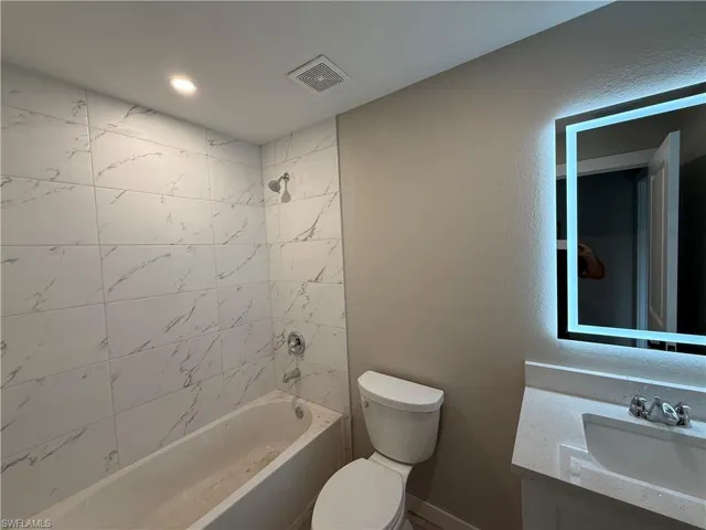 Full bathroom with toilet, vanity, and tiled shower / bath combo