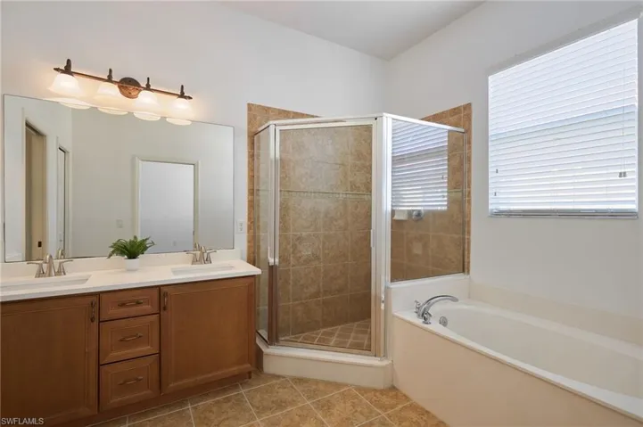 Bathroom featuring shower with separate bathtub, tile patterned floors, and double vanities