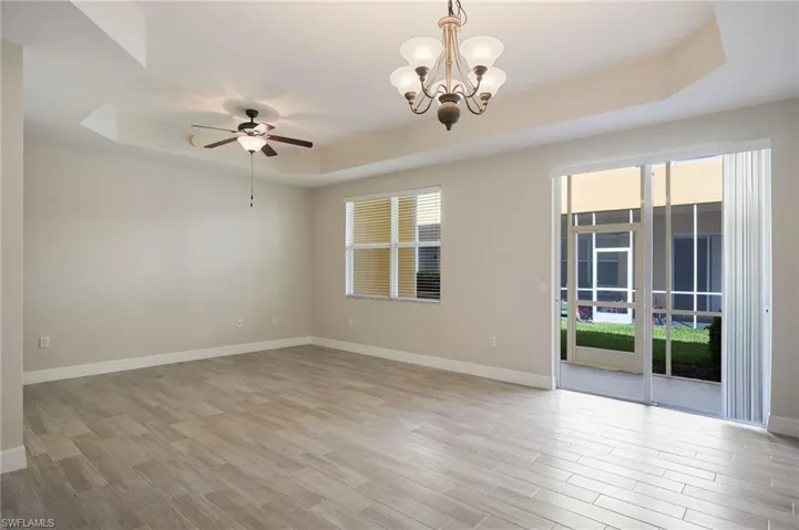 Living area with ceiling fan with notable chandelier, a tray ceiling, and plenty of natural light
