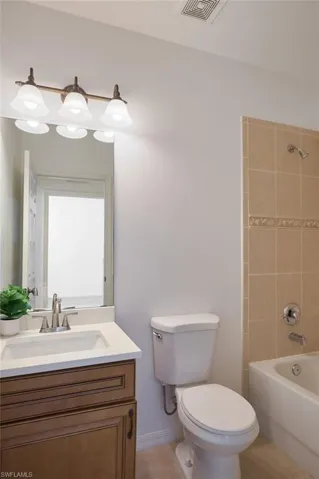 Full bathroom featuring vanity, toilet, tile patterned floors, and tiled shower / bath
