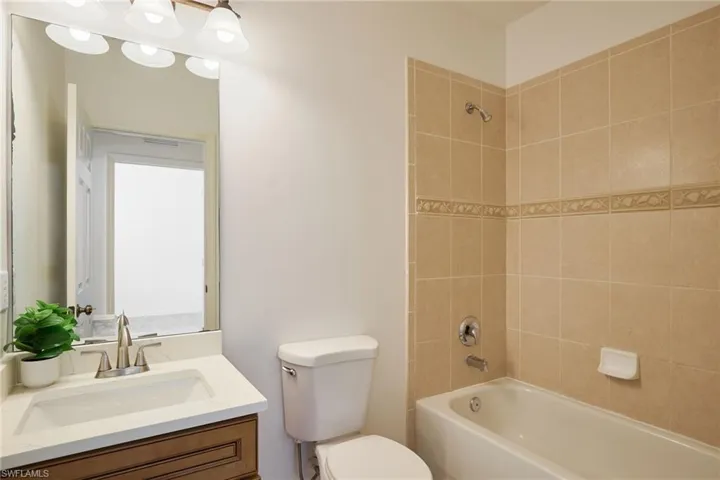 Full bathroom with tiled shower / bath, vanity, and toilet