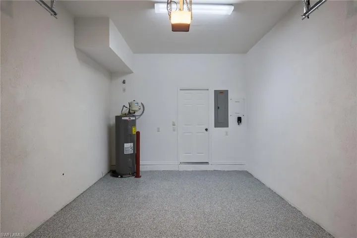 Garage featuring a garage door opener, water heater, and electric panel with epoxy floors