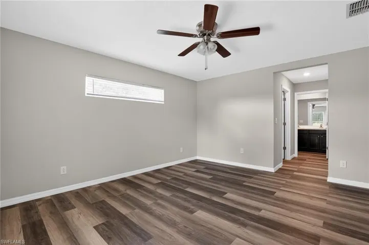 Spacious room featuring wood-finish flooring, a ceiling fan with integrated lighting, and a horizontal window with blinds