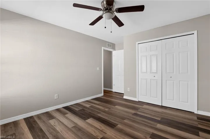 Spacious room featuring wood-finish flooring, light neutral-toned walls, and a ceiling fan