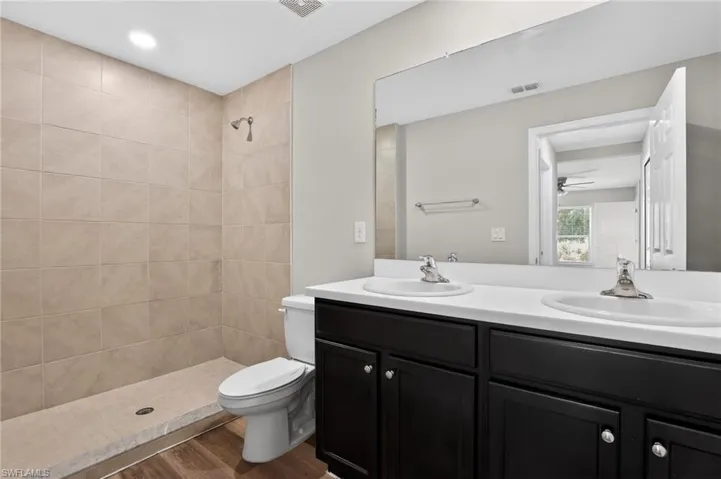 Bathroom featuring a dual-sink vanity with dark cabinetry, white countertops, and brushed nickel fixtures