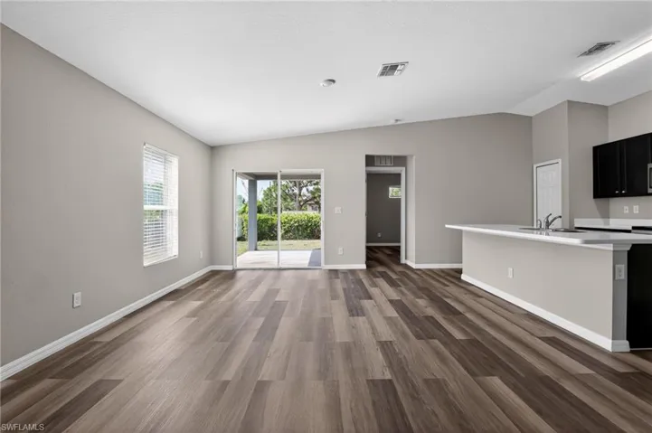 Open-concept living space featuring wood-finish flooring, neutral wall tones, and a vaulted ceiling