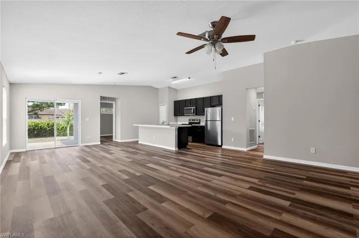 Open-concept living area with wood-finish flooring extending into the kitchen