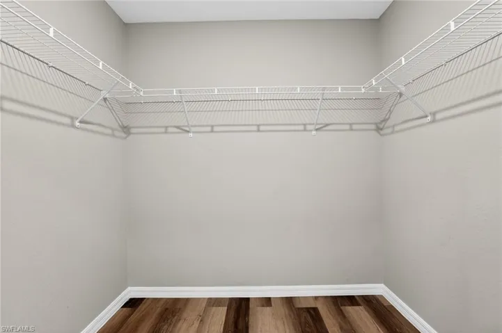 Closet space featuring wire shelving, wood-finish flooring, light gray walls, and white baseboards