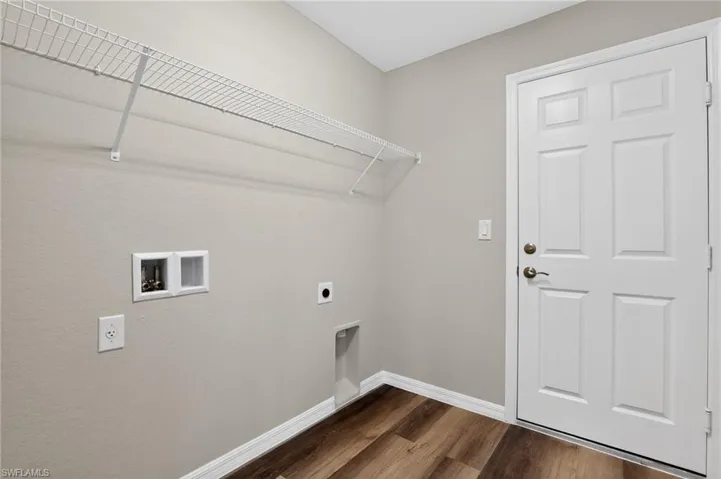 Utility space featuring wood-finish flooring, light neutral wall paint, and white trim