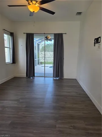 Spare room with dark wood-style floors, plenty of natural light, and a ceiling fan