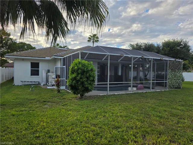 Rear view of house with glass enclosure, a sunroom, a tile roof, and stucco siding