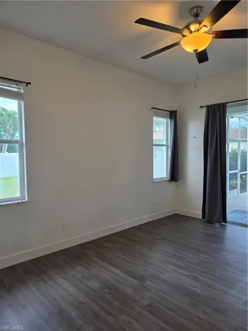 Empty room with dark wood-type flooring and a ceiling fan